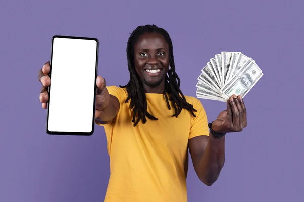 快乐富有的年轻的非洲裔美国人 喜欢随意地展示带有白色空屏幕的智能手机 在紫色工作室背景下进行现金交易 在股票和市场上进行在线交易 他们很幸运 受到了嘲笑 — 图库照片
