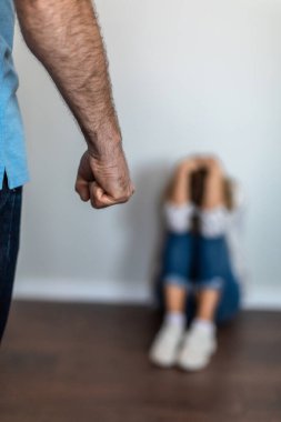 Orta yaşlı üzgün Avrupalı kadın elleriyle başını örtüyor, yerde yumruğu olan agresif bir adamdan dayak yiyor. Şiddet, ilişki sorunları ve ev içi şiddet covid-19 salgınından kaynaklanıyor