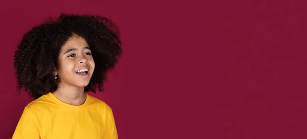 兴奋的漂亮可爱的年轻黑人女孩 一头浓密的金发 穿着黄色的T恤 看着复制的空间为广告和微笑 五彩缤纷的勃艮第工作室背景 — 图库照片