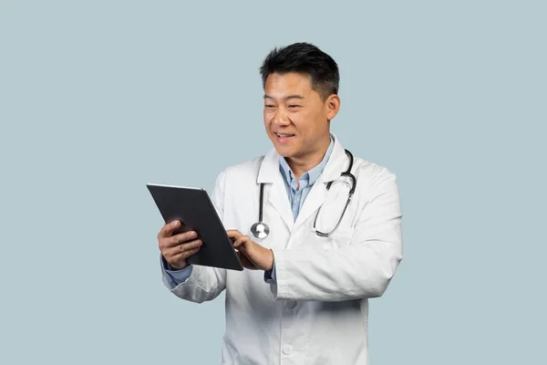 Alegre Terapeuta Masculino Chinês Meia Idade Casaco Branco Digitando Tablet — Fotografia de Stock