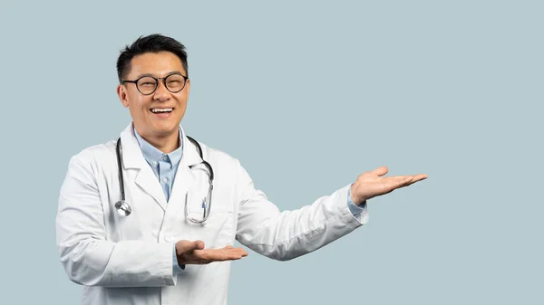 Wesoły Dojrzały Chiński Lekarz Białym Płaszczu Okulary Wskazują Pustą Przestrzeń — Zdjęcie stockowe