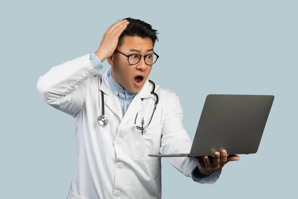 Smutny Wstrząśnięty Dojrzały Chiński Lekarz Białym Płaszczu Okulary Laptopem Trzymać — Zdjęcie stockowe