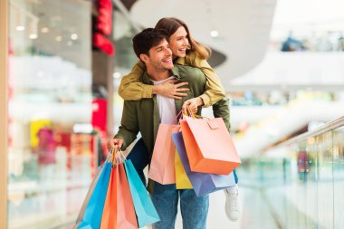 Birlikte alışveriş yapan bir çift, koca, eş sırtında renkli kağıt torbalarıyla hipermarkette poz veriyor. Kara Cuma Teklif, Mevsimsel Satış Konsepti
