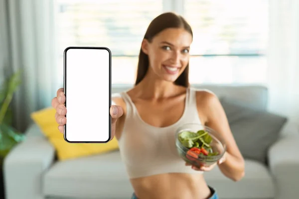 体重减轻应用 将女士展示手机与空白屏风配戴蔬菜沙拉在家减肥 有选择地关注智能手机 饮食应用概念 浅色深度 — 图库照片