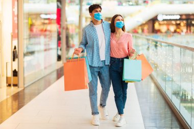 Koca ve Kadın Alışveriş Merkezi 'nde renkli alışveriş torbaları taşıyan yüz maskeleri takıyor. Alıcılar Hypermarket 'te vakit geçiriyorlar. Büyük Mevsimlik Satış Teklifi Konsepti