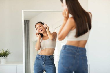 Millennial Kadın Kulaklık Giyiyor Şarkı Söylüyor Ayna Pozisyonu Dinliyor ve Evde Eğleniyor. Müzik Uygulaması, Harika Parça Listesi Konsepti. Seçici Odaklanma