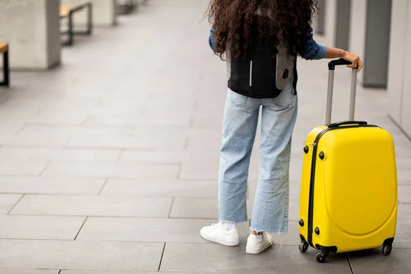 难以辨认的女人 留着长长的卷发 随手带着黄色的行李和背包 带着卷曲的长发 在机场等候航班 带着黄色的行李和背包 带着剪裁的背景色 复印广告空间 — 图库照片