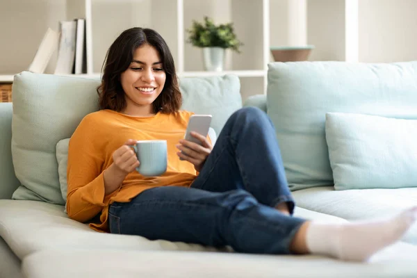 Smiling Young Arab Woman Resting Couch Smartphone Coffee Cheutful Middle — 스톡 사진