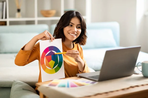 Tutoring Concept. Smiling Young Arab Female Graphic Designer Demonstrating Color Swatches At Laptop Web Camera, Happy Middle Eastern Tutor Lady Making Online Lesson From Home, Copy Space