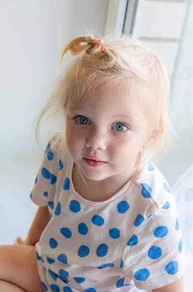 Retrato de cerca de la adorable niña sentada en el alféizar de la ventana — Foto de Stock