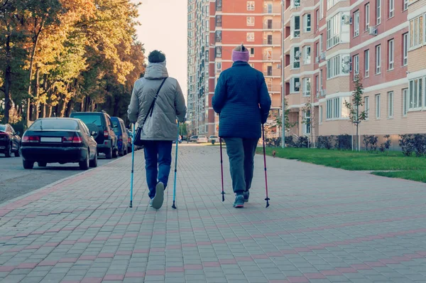 Két idős nő nord sétapálcával. A fizikai aktivitás gyakorlása a friss levegőn. — Stock Fotó