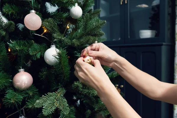 Kadınların elleri Noel ağacını toplar ve oyuncaklarla süslüyor. Yeni yıl havası. Parti ve tatil kutlaması konsepti