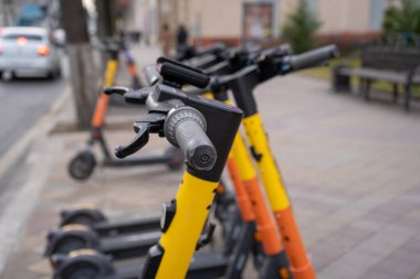 Elektrikli şehir ulaşımı. Asfalt taşının üzerinde akümülatörlerle motosiklet sürmek için bir sıra elektrik hazır..