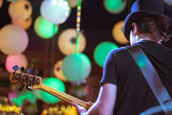 Electric Bass gitaristi sahnede. Müzisyenin arka görünümü.