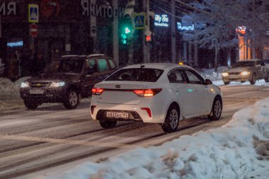 Krasnodar, Rusya - 23 Ocak 2022: Arabalar akşam karlı bir yolda gidiyor. Araba ıslak kaygan yolda hareket halinde..