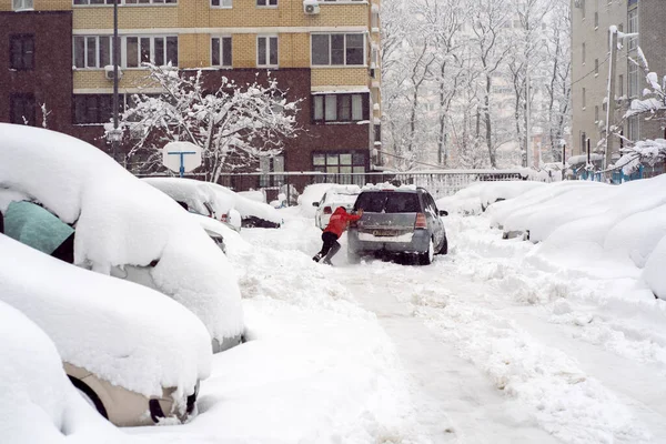 Краснодар, Россия - 23 января 2022 года: человек толкает автомобиль по покрытой снегом дороге — стоковое фото