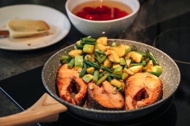 Izgara alabalık bifteği. Kızartma. Kabak ve yeşil fasulyeler tavada kızartılmış. Elektrikli hob.