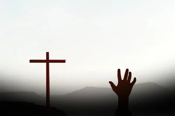 从代表耶稣的十字架寻求帮助的人的手轮廓 — 图库照片
