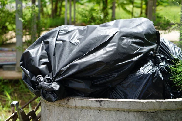 black bag overflowed from the garbage collector.