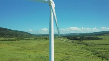 Geniş rüzgar türbinleri. Saha manzaralı, parlak turuncu günbatımı. Mavi gökyüzü parkı yavaş çekim drone dönüşü. Siluetler yel değirmenleri, büyük turuncu güneş diski yaz merceği parlamaları. Alternatif enerji