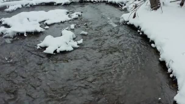 冬の雪に覆われた湖の上の無人機からの早朝の晴れた空の景色では、川は冷たい雪のカーペットで覆われています. — ストック動画