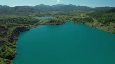 Mükemmel yuvarlak şekilli küçük bir göl üzerinde havadan aşağıya doğru uçuyor. Bulutlu gökyüzü, ağaçlar ve bitkilerle çevrili göletin berrak turkuaz suyuna yansıyor. Yazın yukarıdan dokunulmamış doğa..