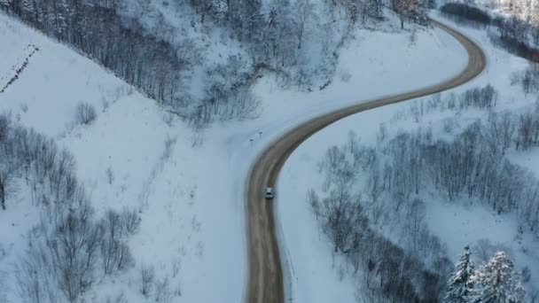 Снежная дорога проходит в лесу в горах через перевал в декабре. Автомобиль, проезжающий зимой по заснеженному лесу по проселочной дороге зимой. — стоковое видео