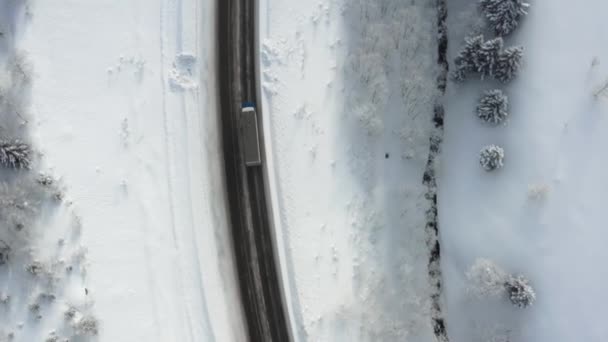 Zasněžená cesta vede lesem v horách prosincovým průsmykem. Autem projíždí zimní zasněžený les na venkovské silnici v zimním shora pohled. — Stock video