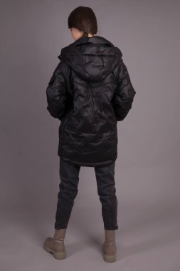 Stüdyoda gri arka planda giysileri gösteren bir model çekmek. Genç bir kız model kameraya poz veriyor. Kıyafetleri farklı pozisyonlarda gösteriyor..