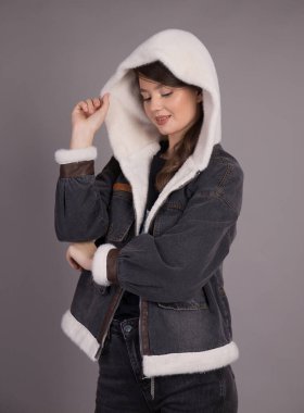 Kameraya poz veren genç bir kız model farklı pozisyonlarda giysiler sergiliyor. Gri arka planda bir elbise stüdyosunda bir model gösteriliyor..