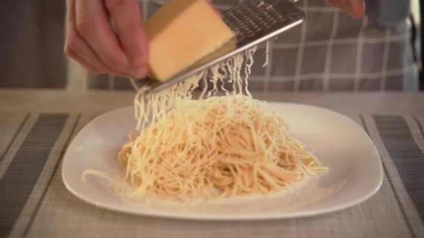 Повар на кухне втирает твердый сыр в тарелку макарон со свежеприготовленным итальянским сыром для макарон. Со свежеприготовленной итальянской пастой, шеф-повар втирает твердый сыр на железную терку в — стоковое видео