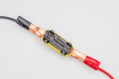 Kırmızı ve siyah kablo otomotiv klipleri ya da beyaz arka planda sarı oyuncak bir arabanın akü kıskaçları. Kışın otomobil motorunu çalıştırmak, pilin hızlı bir şekilde başlatılması konsepti.