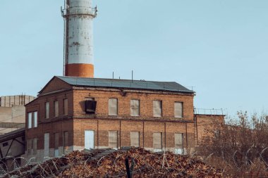 Sonbahar ısıtma mevsiminde yakındaki bir termik santralde tüttüren kırmızı ve beyaz borular. Endüstriyel arazi. Çevreye zarar verme kavramı.