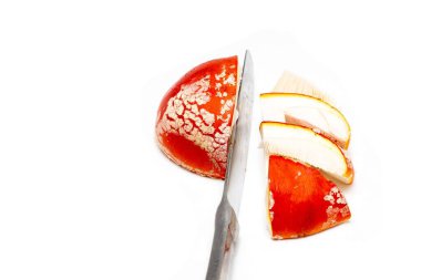 Beyaz bir arka planda masa bıçağıyla kesilmiş kırmızı bir sinek (amanita muscaria) şapkası. Zehirli mantar mantar mantarı konsepti, halüsinojen ve uyuşturucu kullanımı.
