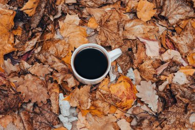 Sonbahar sarı yapraklarının arka planında bir fincan beyaz kahve..