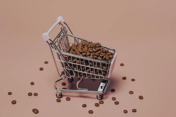 Cat or dog pet food in a shopping cart on a pink background. The concept of wholesale purchase of feed, pet store.