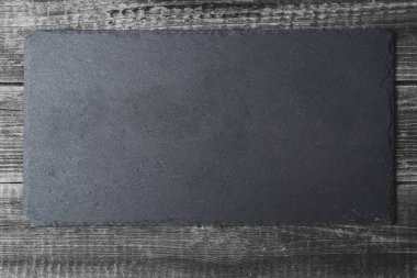 Ahşap masa zemininde boş siyah bir tahta kesme tahtası. Kopyalama alanı eklenecek yerdir.