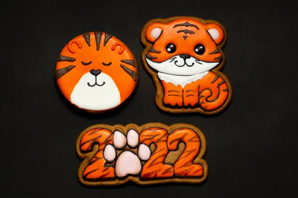 生姜饼干的形式是一个五彩斑斓的老虎形象和数字2022年的老虎着色橙色釉料在黑色背景 — 图库照片