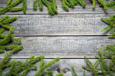 Yeşil köknar dallarıyla mutlu Noeller. Gri ahşap bir masada Noel ağacı dalları. Metin veya nesneler için boşluk kopyala.