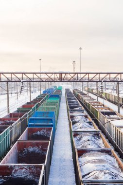 Railway station. Freight trains carrying natural resources with a view from above. Empty wagons on the tracks. Bright winter industrial landscape russian. Sunrise or sunset over the railroad.