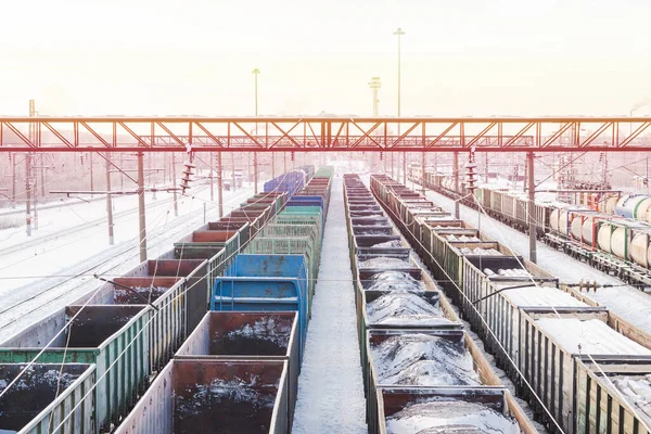 Railway station. Freight trains carrying natural resources with a view from above. Empty wagons on the tracks. Bright winter industrial landscape russian. Sunrise or sunset over the railroad.