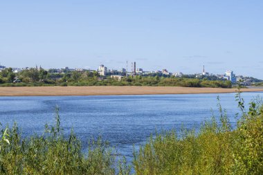 Nehrin karşısındaki sanayi bölgesinin manzarası. Fabrika borularıyla yaz yeşili ülke manzarası.