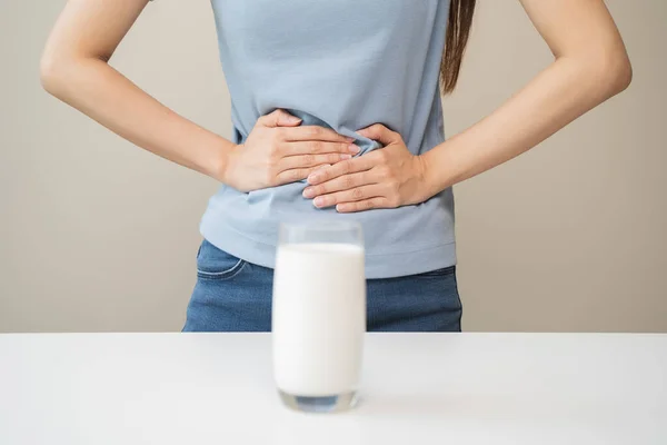 Laktoz intolerans konsepti. Kadın elinde bir bardak süt tutuyor ve midesi ağrıyor..