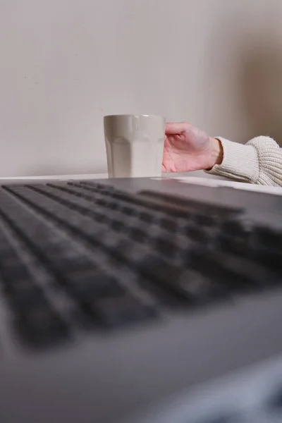 Dizüstü Bilgisayarın Önünde Bir Fincan Çay Kahve Tutan Bir Elin — Stok fotoğraf