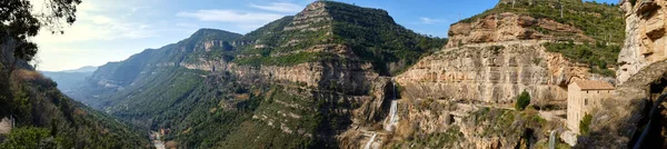 バルセロナの岩や滝の自然山岳地帯であるサンミケル ファイ修道院のパノラマビュー ストック写真