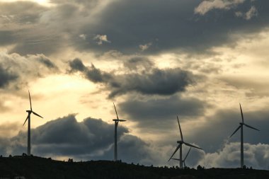 Rüzgar türbinleri gün batımında dağlarda bir rüzgar çiftliğinde. yeşil ekolojik enerji.