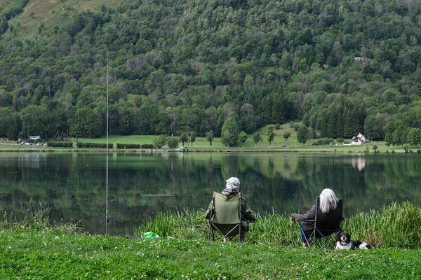 无法辨认的老夫妇 退休人员在大自然中自由自在地坐在湖边钓鱼 — 图库照片