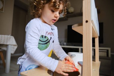 Küçük kız evde oyuncak mutfağıyla yemek pişiriyor..