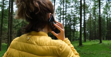 Ormanda cep telefonu kullanan bir kadın