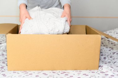 Kışlık kıyafetleri karton kutuya koyan bir kadın. Bağış kavramı.